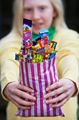 Girl holding a bag of assorted childrens retro sweets and candy - Stock Image - D5JGBY - D5JGBY