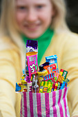 Girl holding a bag of assorted childrens retro sweets and candy - Stock Image - D5JG98 - D5JG98